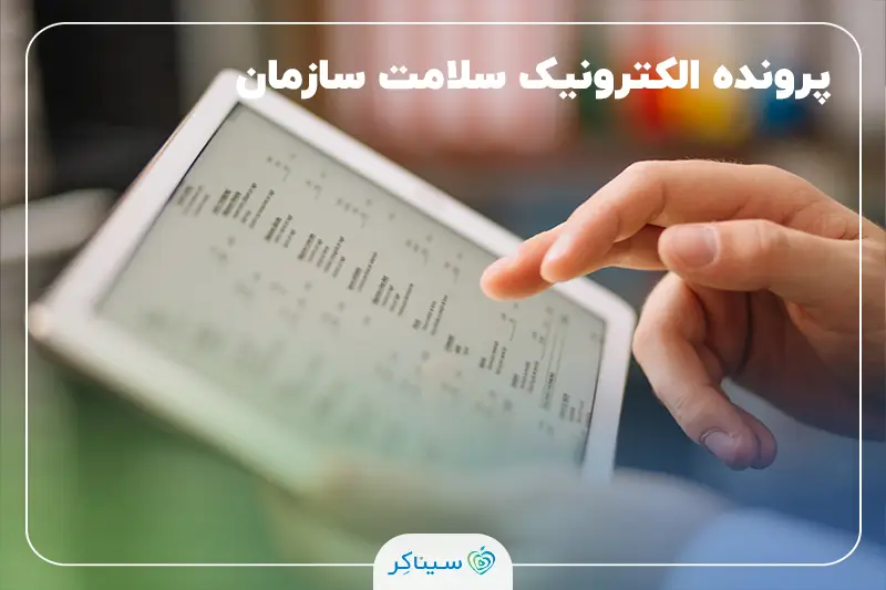 نمای نزدیک از دست فردی که با استفاده از تبلت در حال مشاهده و مدیریت پرونده الکترونیک سلامت است.